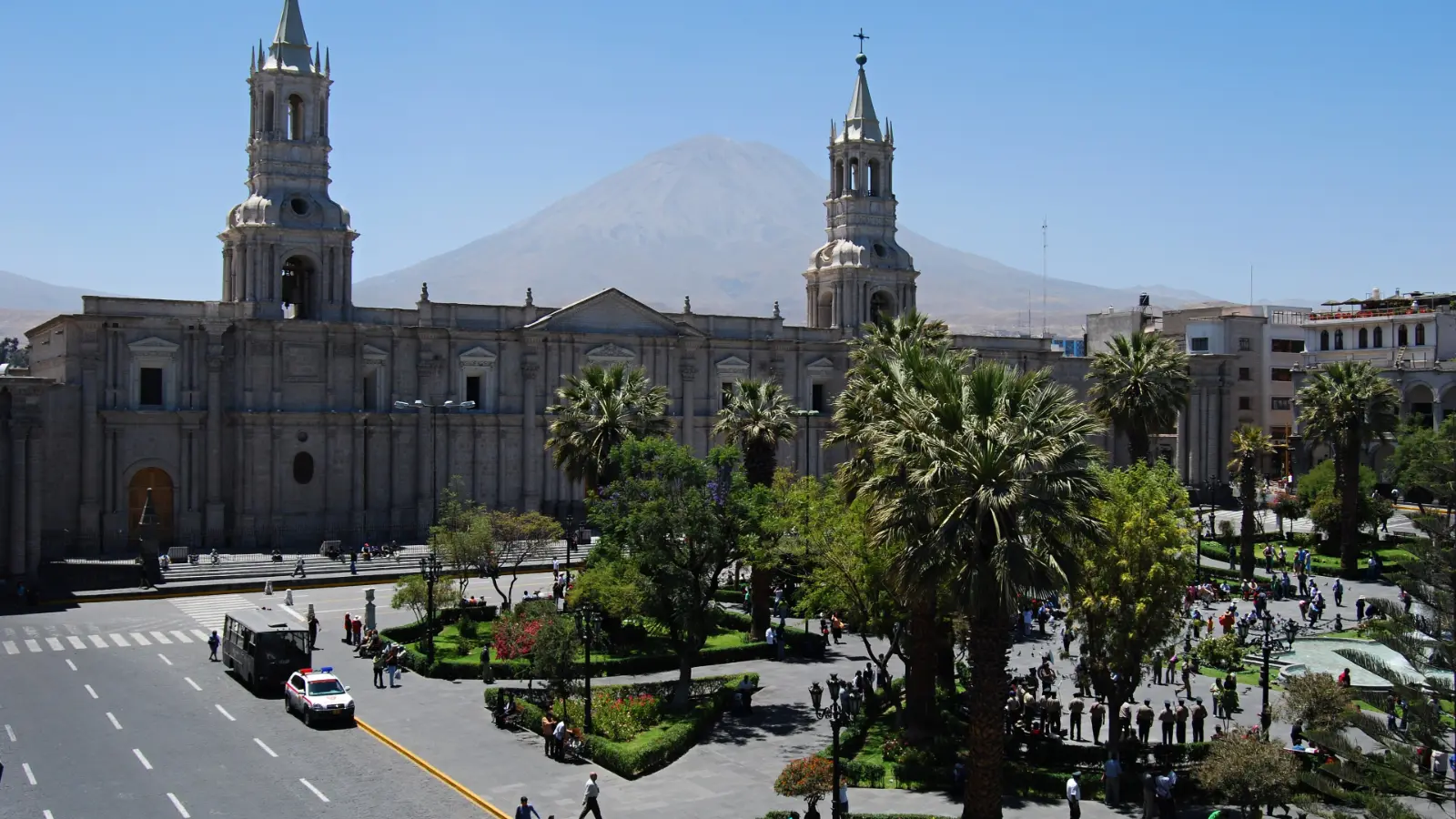 Plaza de Armas of Arequipa with palm trees, stone arcades and the cathedral, El Misti behind